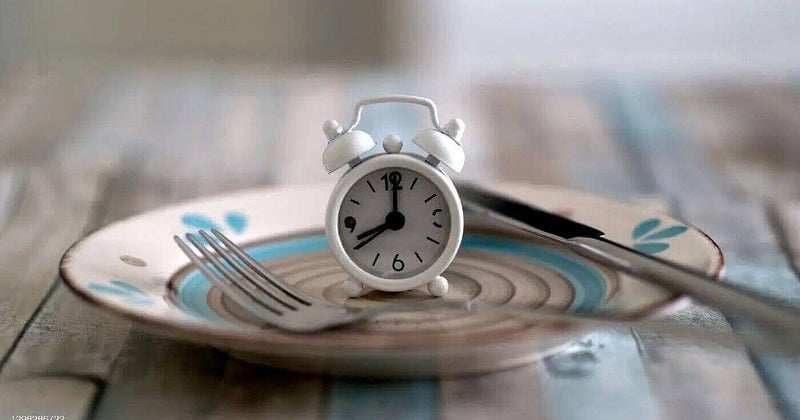 Person practicing intermittent fasting with healthy foods, illustrating time-restricted eating for lifespan and health